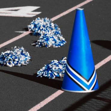 A blue megaphone and pom poms are positioned on a football field.